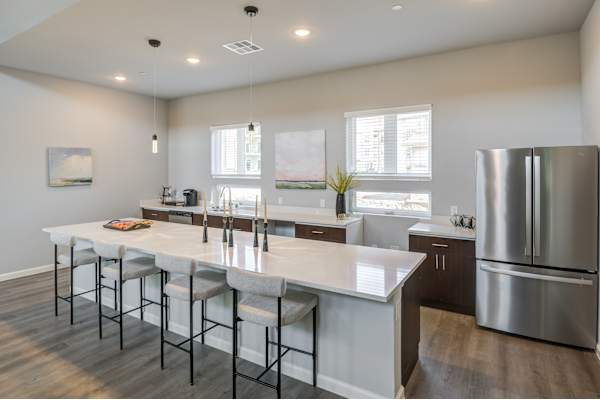 an open kitchen with a large island and stainless steel refrigerator